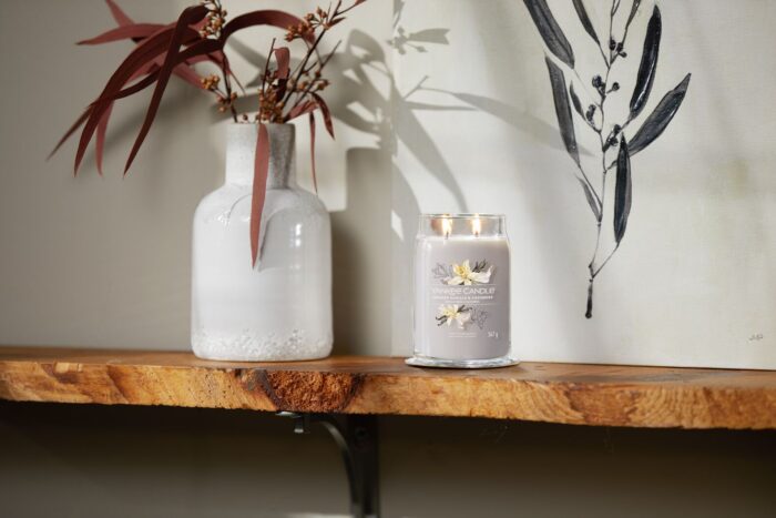 Yankee Candle Duftkerze mit zwei Flammen neben Vase und Wandbild