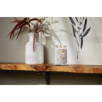 Brennende Yankee Candle Smoked Vanilla & Cashmere Kerze auf einem Holzregal