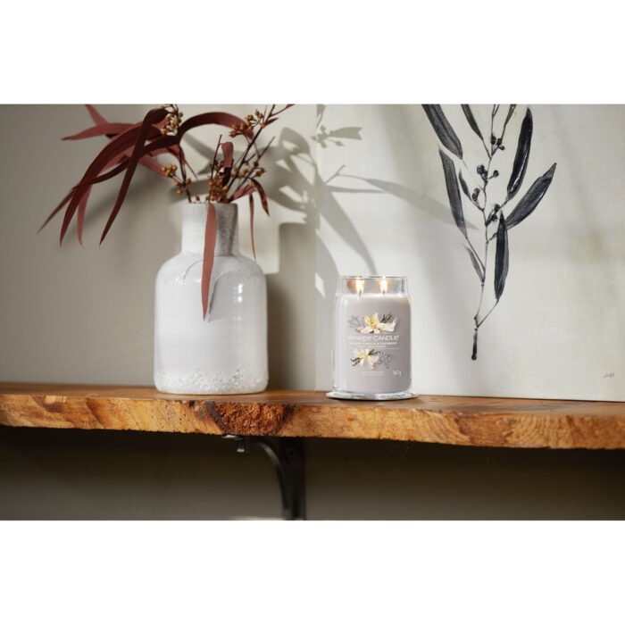 Brennende Yankee Candle Smoked Vanilla & Cashmere Kerze auf einem Holzregal