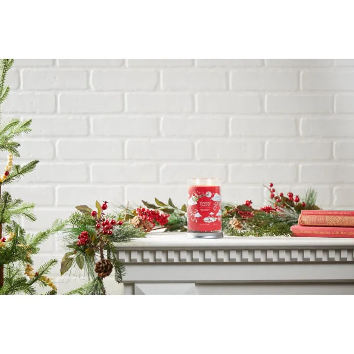 Rote Yankee Candle Kerze zwischen Tannenzweigen und Weihnachtsbüchern
