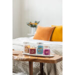 Vier Yankee Candle Glaskerzen, eine davon brennend, auf einem Holztablett