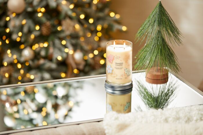 Brennende Christmas Cookie Kerze auf Spiegeltisch neben dekorativem Tannenbaum