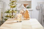 Brennende Christmas Cookie Kerze vor Weihnachtsbaum und dekorativen Glasgefäßen