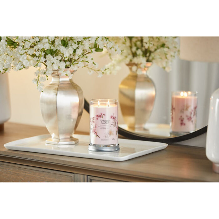 Brennende Yankee Candle Kerze auf einem weißen Tablett neben Blumenvasen