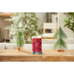 Red Apple Wreath Kerze auf einem Tisch zwischen Weihnachtsdekoration