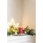 Brennende Red Apple Wreath Kerze auf einem Teller mit Weihnachtsdekoration