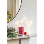 Sparkling Winterberry Kerze neben Weihnachtsdekoration auf einem Tisch
