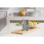 Brennende Black Tea & Lemon Kerze auf Holztablett mit Zitronen im Hintergrund