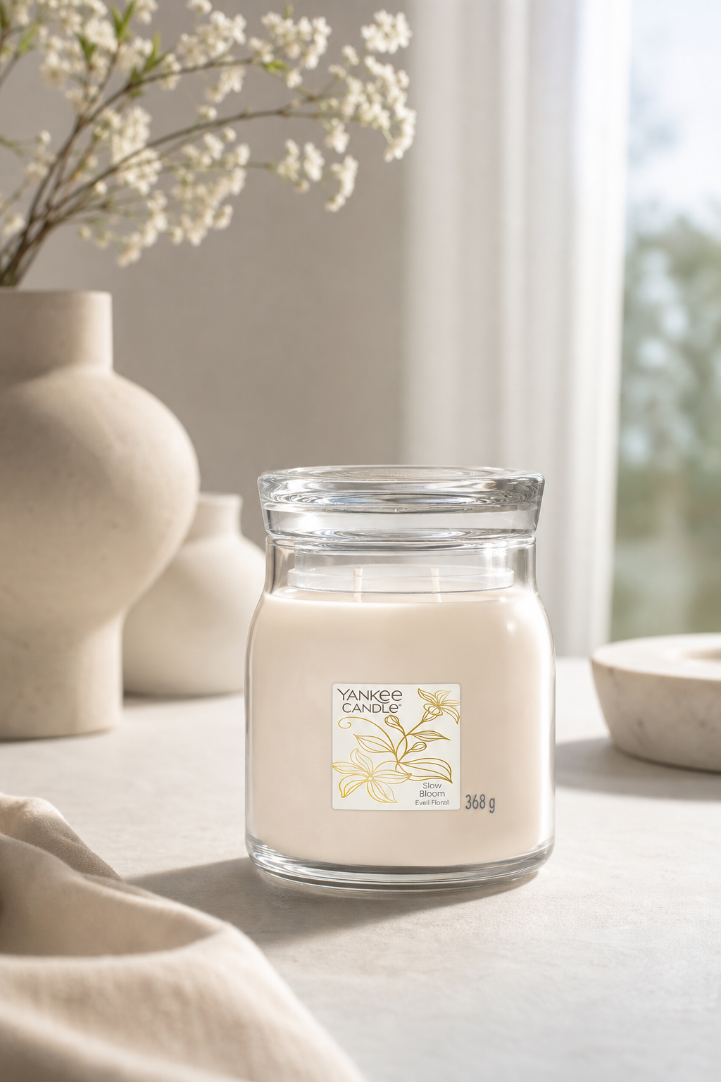 Yankee Candle Slow Bloom Kerze im Glas steht auf einem Tisch