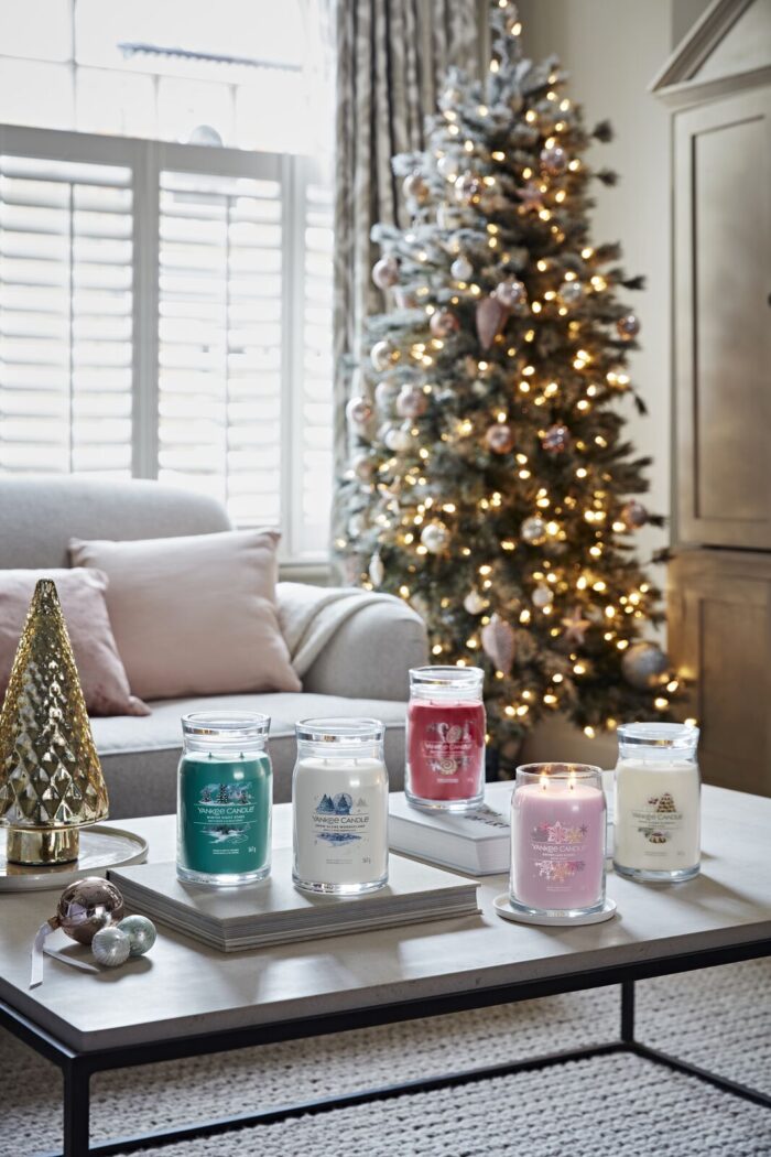 Mehrere Yankee Candle Kerzen auf einem Tisch vor einem geschmückten Weihnachtsbaum