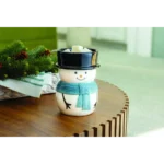 Schneemann-Duftlampe mit Duftwachswürfeln auf einem Holztisch neben Tannenzweigen
