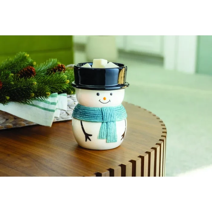 Schneemann-Duftlampe mit Duftwachswürfeln auf einem Holztisch neben Tannenzweigen