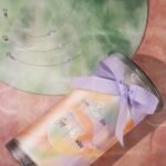 Soft Waves Kerze liegt neben drei Armbändern mit verschiedenen Anhängern