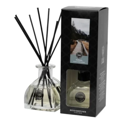 Glasflakon mit schwarzen Duftstäbchen neben der Verpackung des Solitude Reed Diffusers
