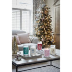 Mehrere Yankee Candle Kerzen auf einem Tisch vor einem geschmückten Weihnachtsbaum