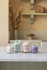 Vier Yankee Candle Gläser mit unterschiedlichen Farben und Etiketten nebeneinander