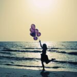 Silhouette einer Person mit Luftballons am Meerstrand