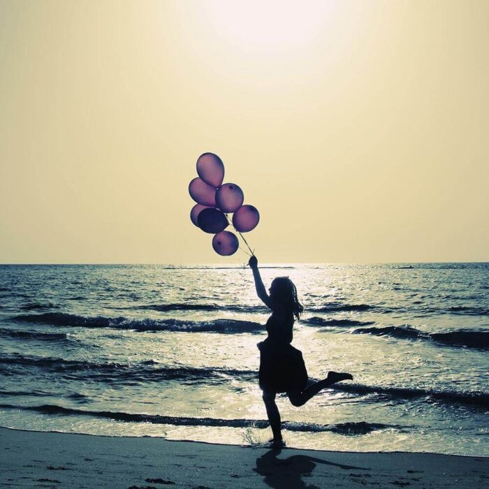 Silhouette einer Person mit Luftballons am Meerstrand