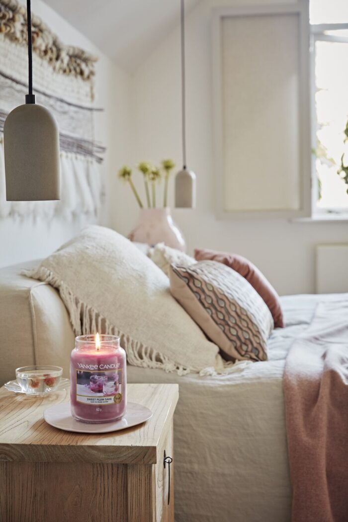 Brennende Yankee Candle Sweet Plum Sake Kerze auf einem Wohnzimmertisch
