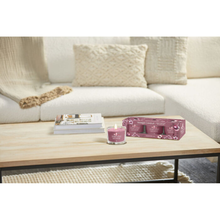 Yankee Candle Sweet Plum Sake Packung und angezündete Votivkerze im Wohnzimmer