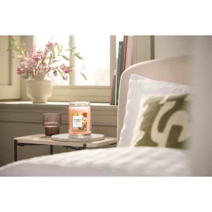 Yankee Candle Jar-Kerze steht auf einem Beistelltisch neben einem Bett