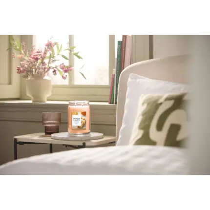 Yankee Candle Jar-Kerze steht auf einem Beistelltisch neben einem Bett