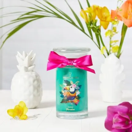 Toucan Paradise Kerze mit Tukanmotiv zwischen weißen Dekorobjekten und Blumen
