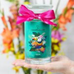JuwelCandle Kerze mit Tukanmotiv und pinker Schleife in einer Hand