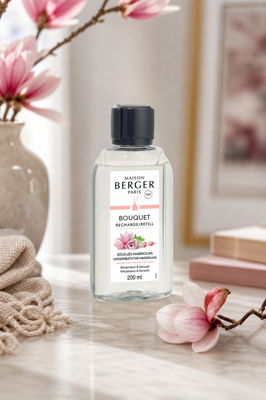 Maison Berger Nachfüller auf Tisch neben Magnolienzweigen und Wohnaccessoires