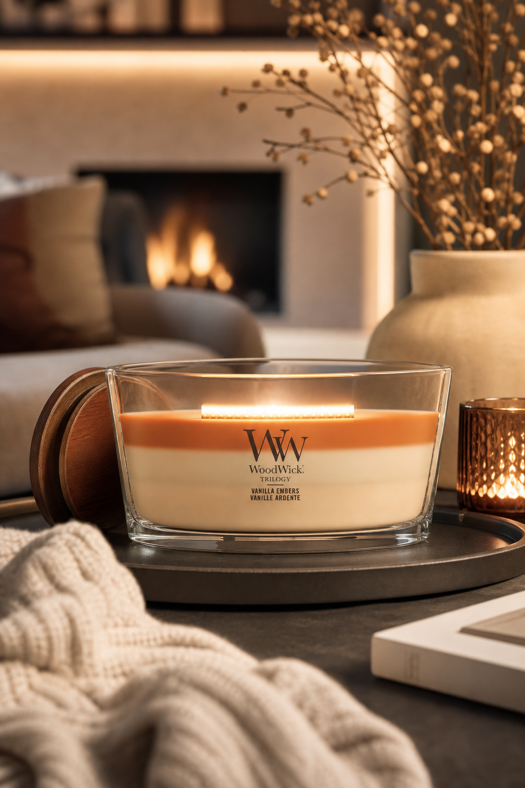 WoodWick Vanilla Embers Kerze brennt auf einem Wohnzimmertisch