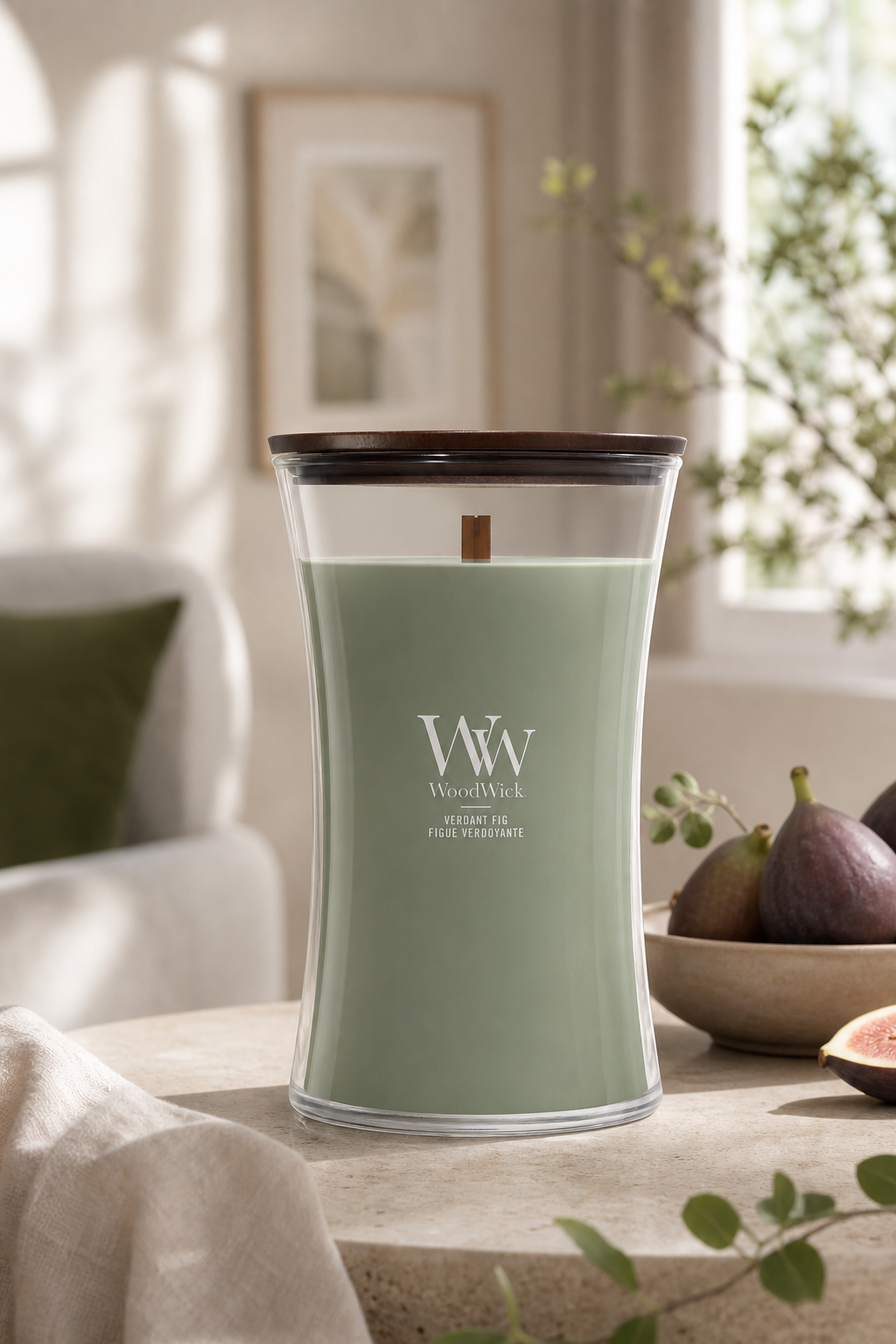 WoodWick Verdant Fig Kerze auf einem Tisch neben einer Schale mit Feigen