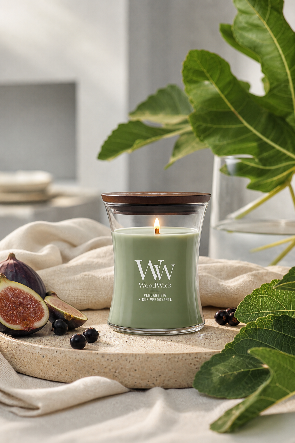 Brennende WoodWick Verdant Fig Kerze auf einem Tisch mit Feigen und Blättern