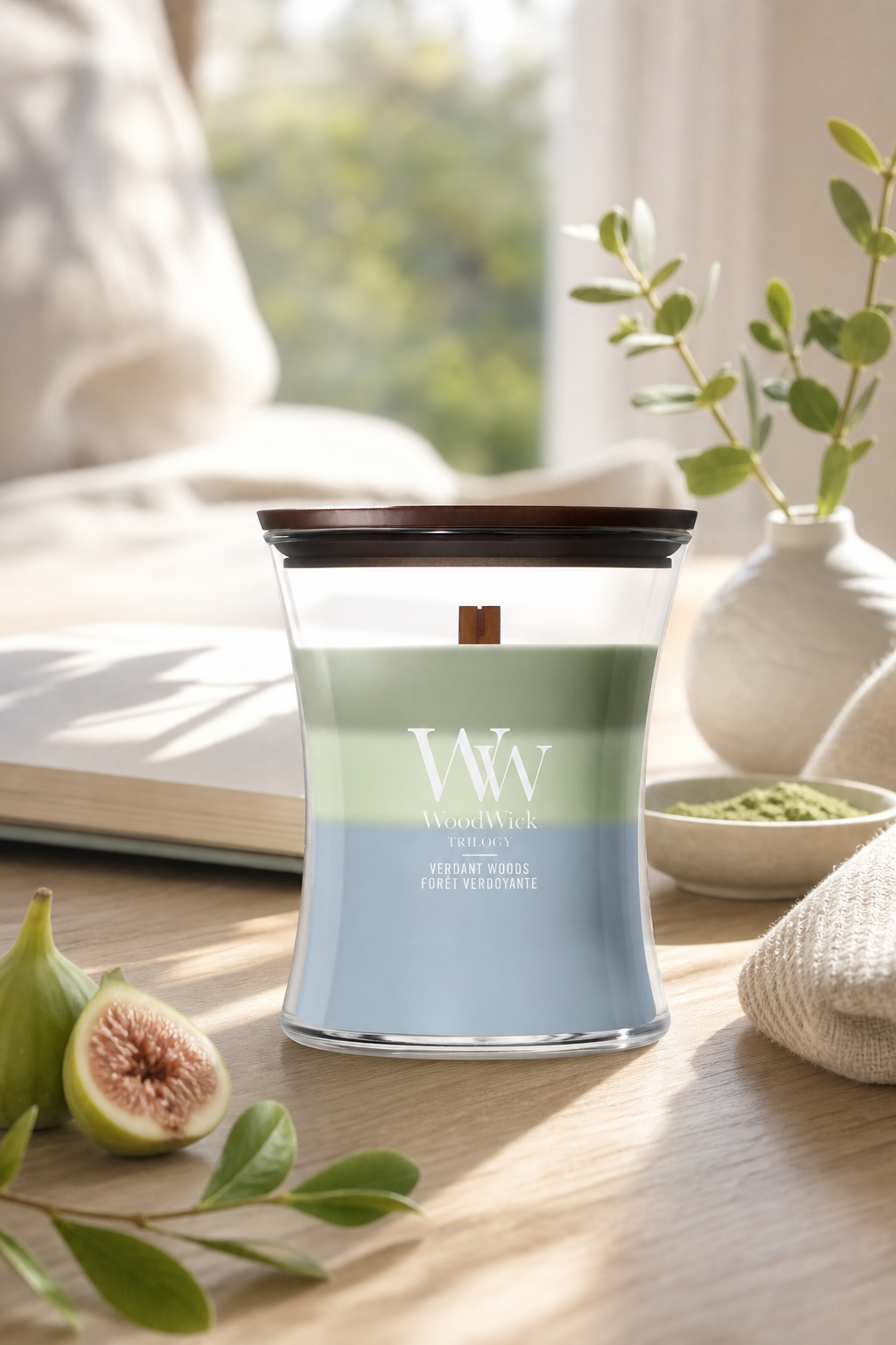WoodWick Verdant Woods Trilogy Kerze mit Deckel auf einem Tisch im Wohnambiente