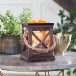 Duftlampe mit Wachswürfeln und leuchtender Edison-Glühbirne auf einem Tisch