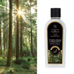 Flasche mit White Cedar & Bergamot Lamp Fragrance vor einem Nadelwald