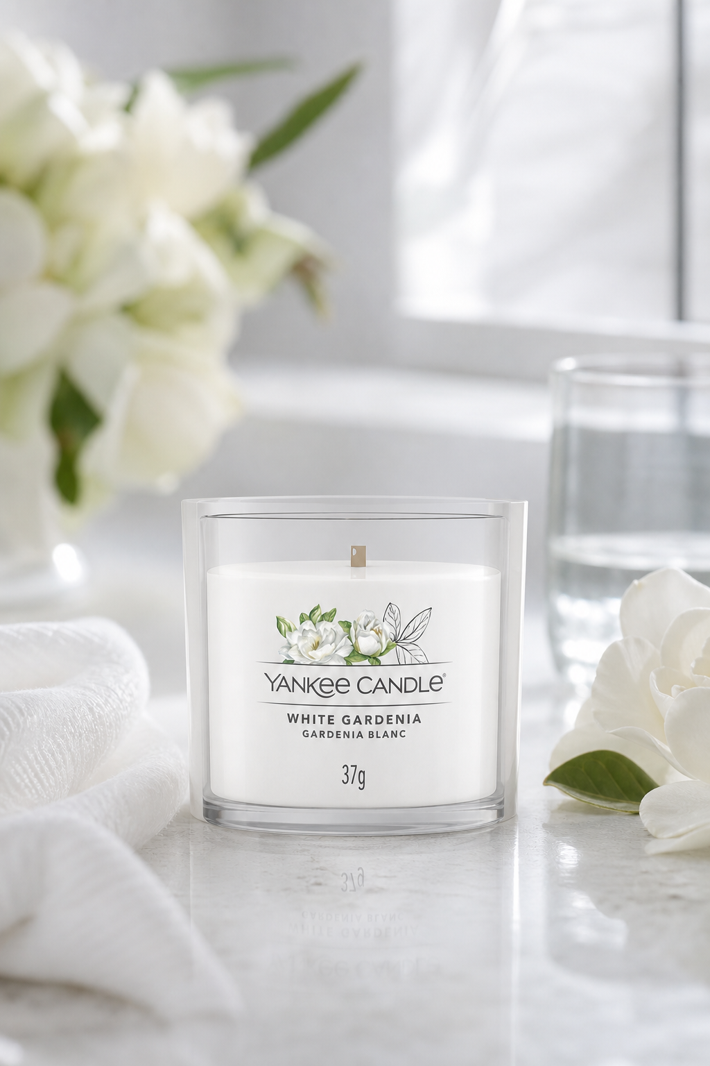 Yankee Candle White Gardenia Kerze im Glas auf heller Oberfläche mit weißen Blumen