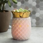 Weiße Ananas-Duftlampe mit grünlichen Wachswürfeln auf einer Fläche