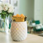 Weiße Ananas-Duftlampe mit orangefarbenen Wachswürfeln auf einem Tisch