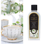 Flasche mit White Tea Lamp Fragrance neben einer weißen Teetasse mit Blumenmotiv