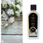 Flasche White Velvet Lamp Fragrance mit weißen Blüten im Hintergrund