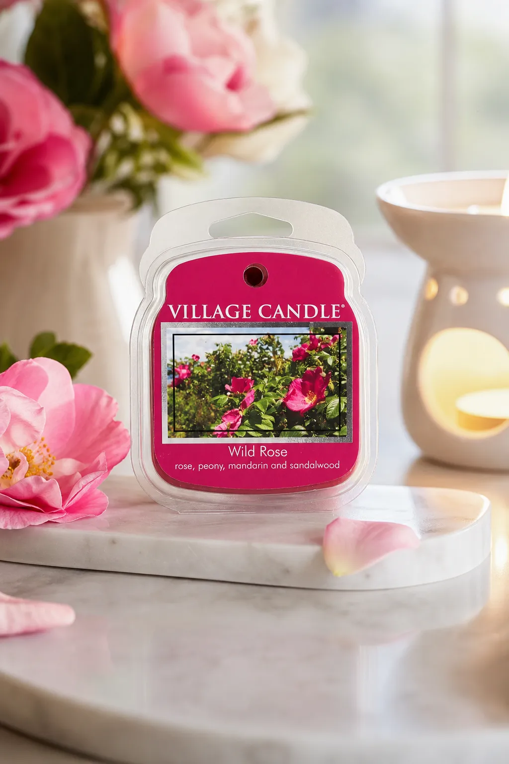 Wild Rose als Wohnszene Village Candle Wild Rose Verpackung auf einer Ablage neben einer Duftlampe